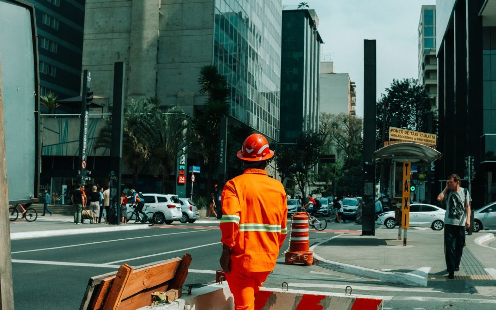 Brasil cria 165,8 mil empregos formais em agosto, mas ritmo anual desacelera Trabalhador em uma rua movimentada de São Paulo, com edifícios e circulação urbana ao fundo.
