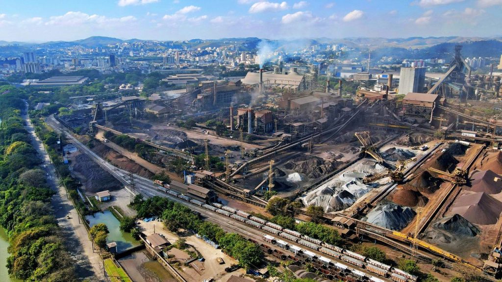 Vista aérea de uma área industrial do Rio de Janeiro, com fábricas e trecho urbano ao redor.