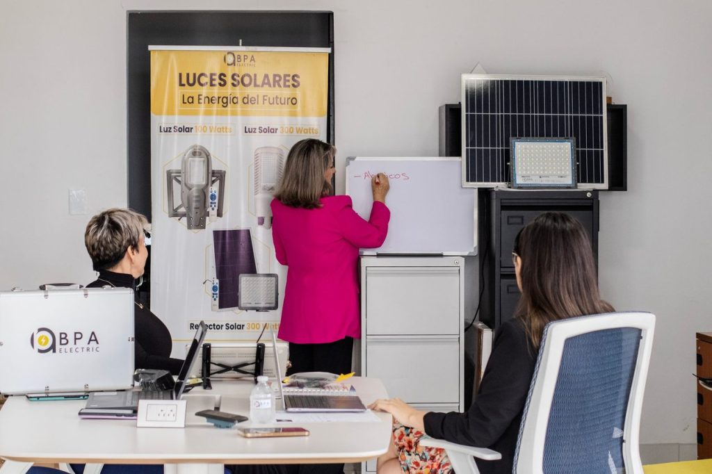 Capital de longo prazo ganha reforço para empresas ligadas à inovação no Brasil Equipe analisa soluções de energia solar diante de painéis e um quadro branco em um escritório.
