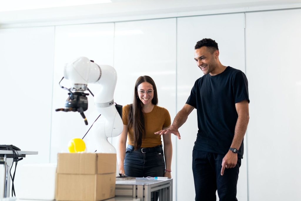 Financiamento adicional amplia alcance de redes de pesquisa em IA na América Latina Dois engenheiros colaboram na avaliação de um protótipo robótico em um laboratório moderno.